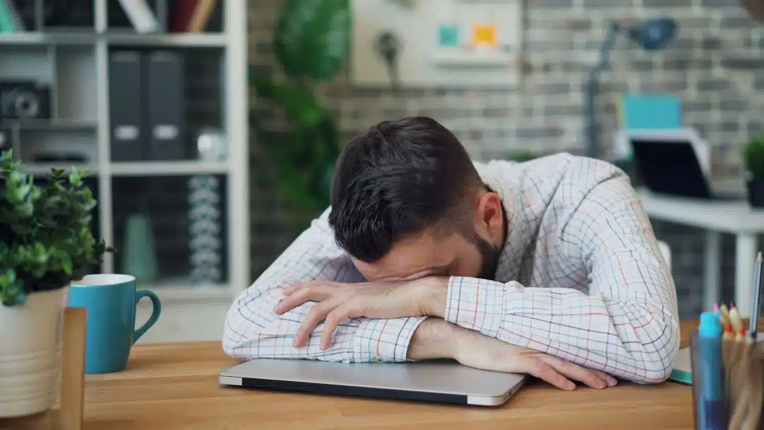 Adult sitting at a desk appearing distracted and overwhelmed, reflecting common ADHD challenges